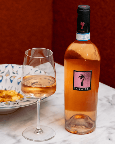 Dettaglio del ristorante Le Quattro Sorelle con bottiglia di vino Palmeri e calicemezzo pieno