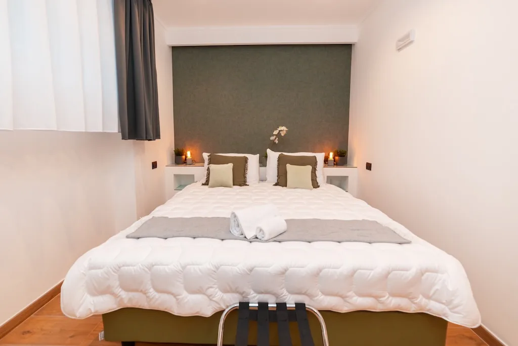 Dettaglio di una camera a Roma con letto matrimoniale pronto per gli ospiti e finestra con tende