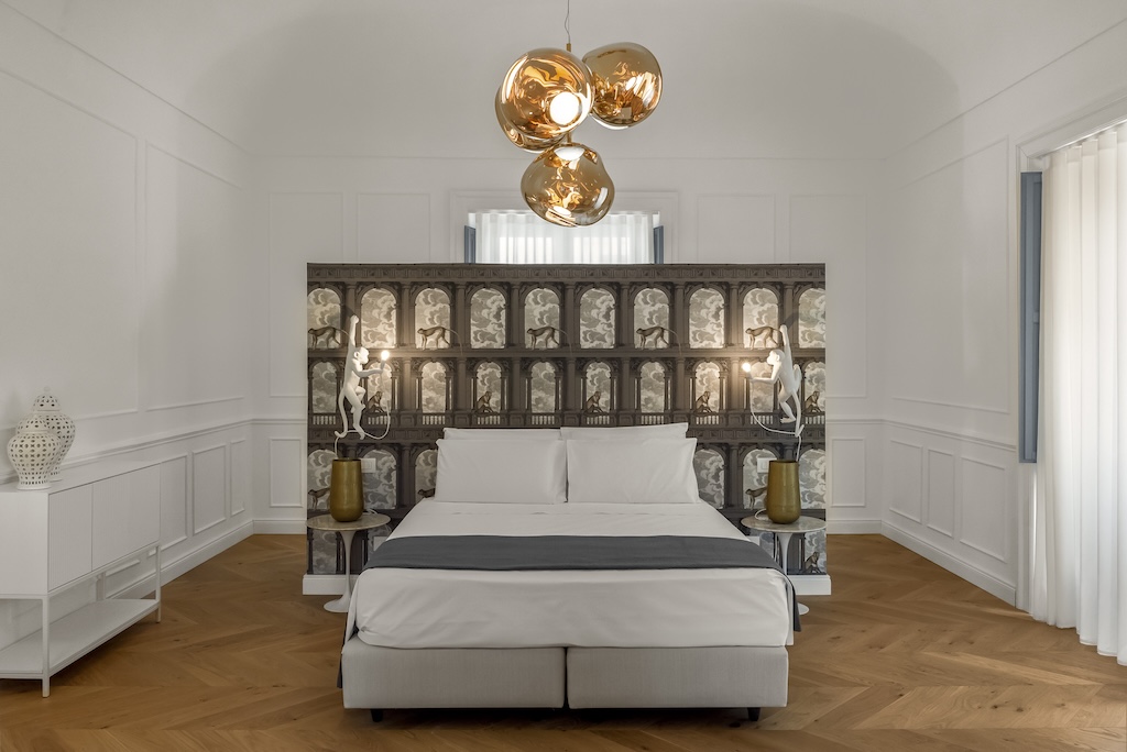 Panoramica del letto dell'elegante suite Nora con comodini, lampade moderne e design artistico