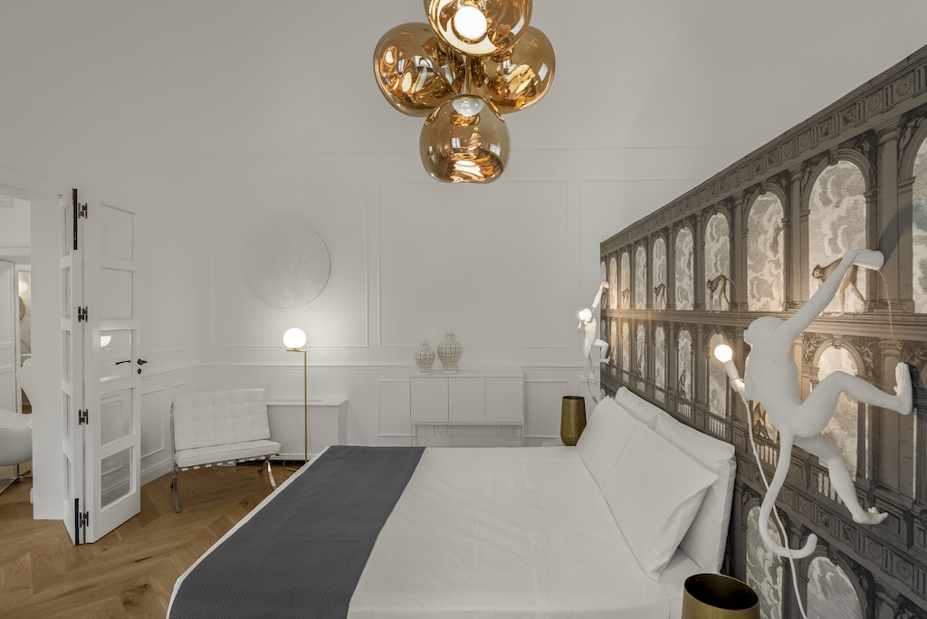 Dettaglio della camera da letto dell'elegante suite Nora con letto, lampade moderne e design artistico