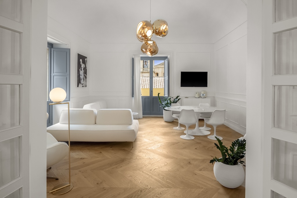 Panoramica del soggiorno dell'elegante suite Nora con tavolo e sedie, divani, lampade moderne e design artistico