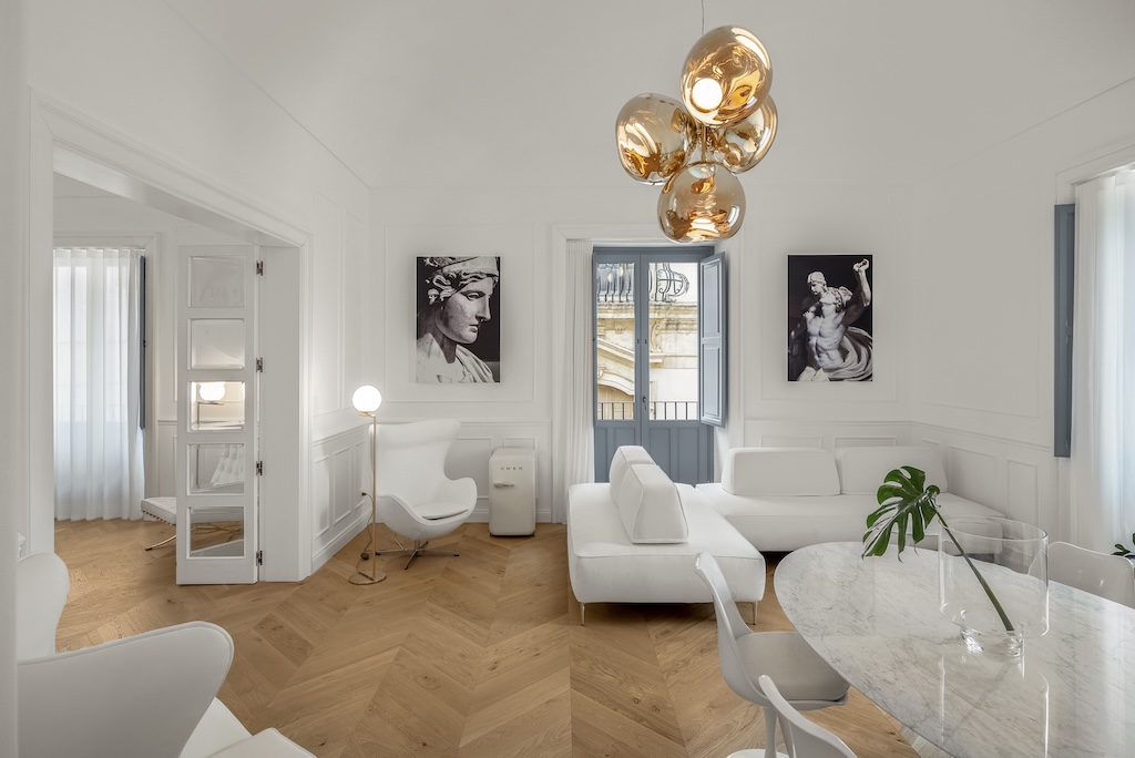Panoramica del soggiorno dell'elegante suite Nora con tavolo e sedie, divani, lampade moderne e design artistico