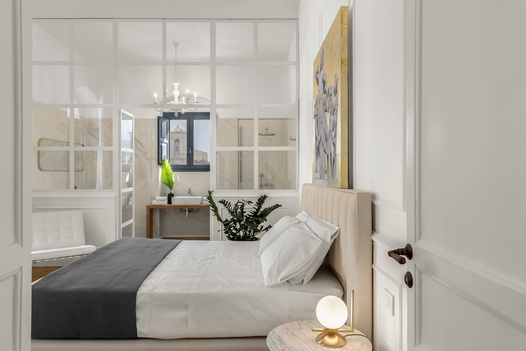 Dettaglio della camera da letto dell'elegante suite Laura con letto, lampada moderna, design artistico e bagno
