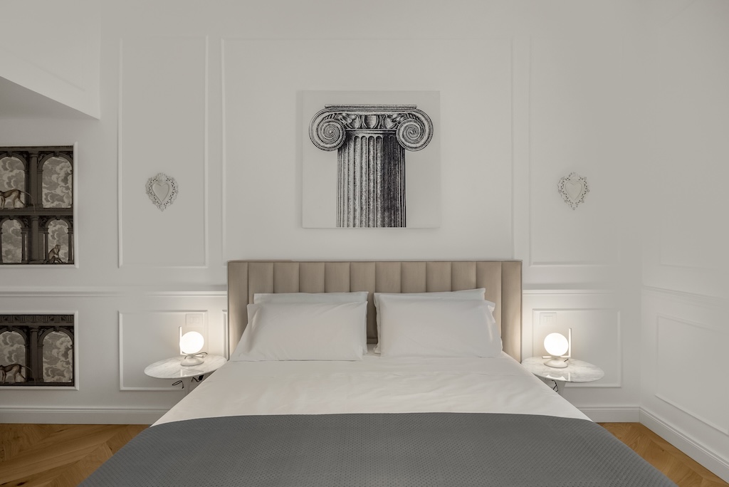 Dettaglio del letto dell'elegante suite Christine con letto, lampade moderne e capezzale artistico