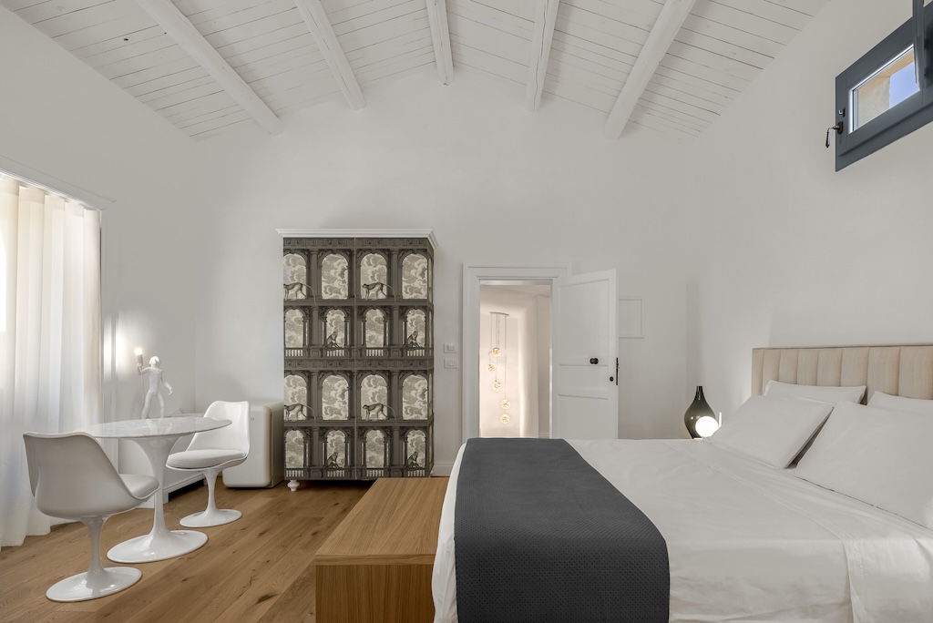 Panoramica della camera da letto della suite Carla con letto, zona giorno e lampade
