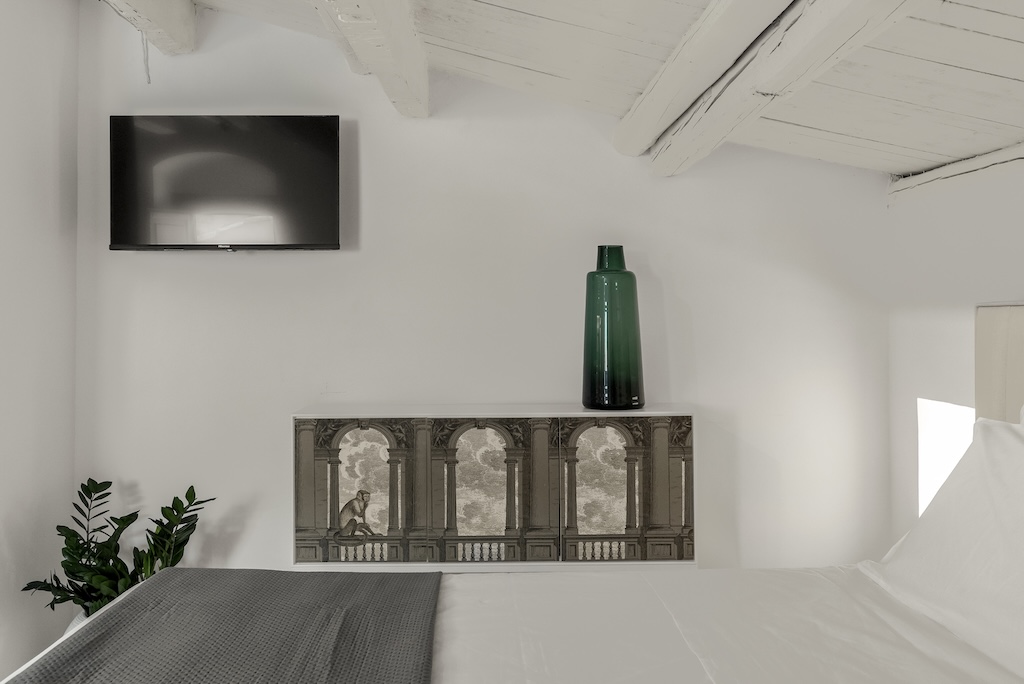 Dettaglio della camera da letto della camera mansardata Carla con letto e TV a muro